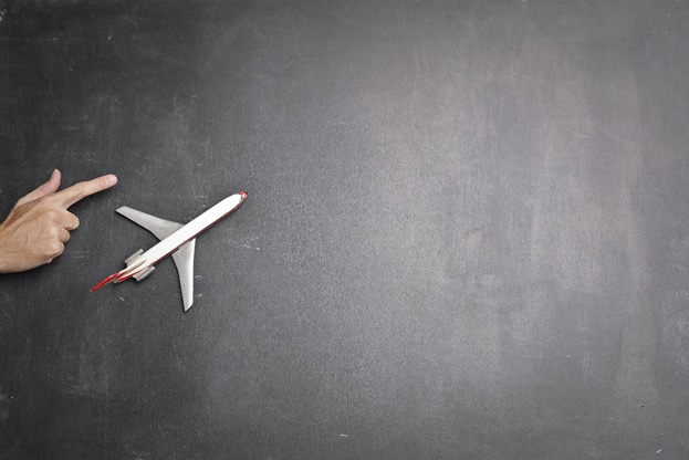 Toy plane and human hand on the chalkboard