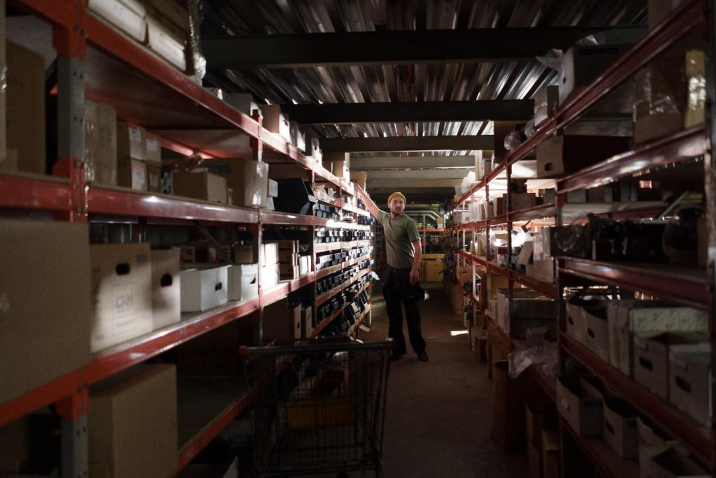 A man in a green t-shirt working in a warehouse