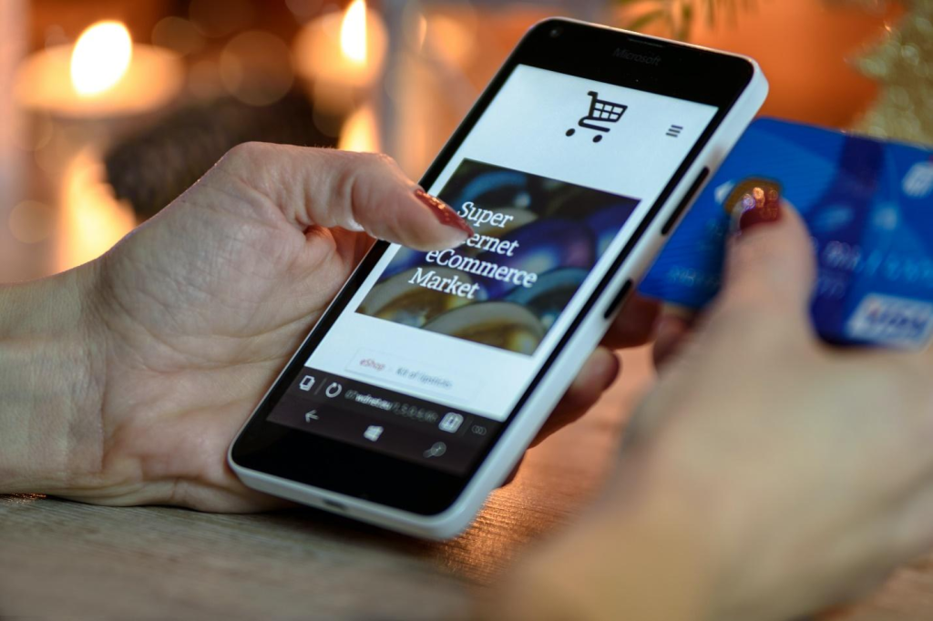 A person holding a phone and a credit card to shop online