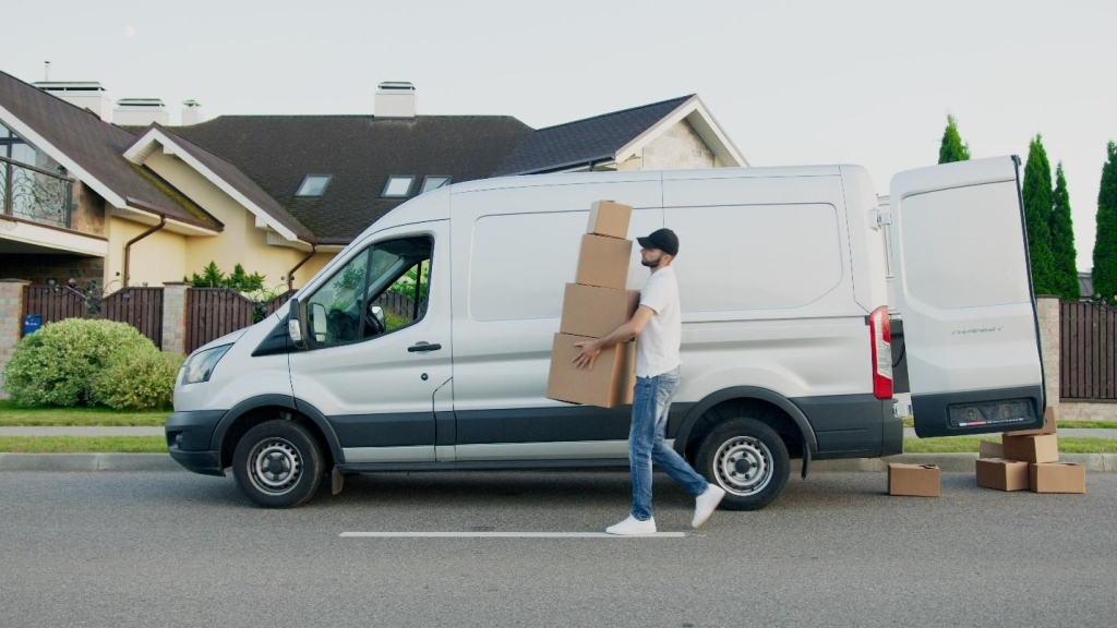 a delivery man carrying boxes outside of a delivery van