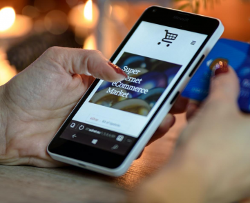 A person holding a phone and a credit card to shop online