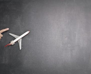 Toy plane and human hand on the chalkboard